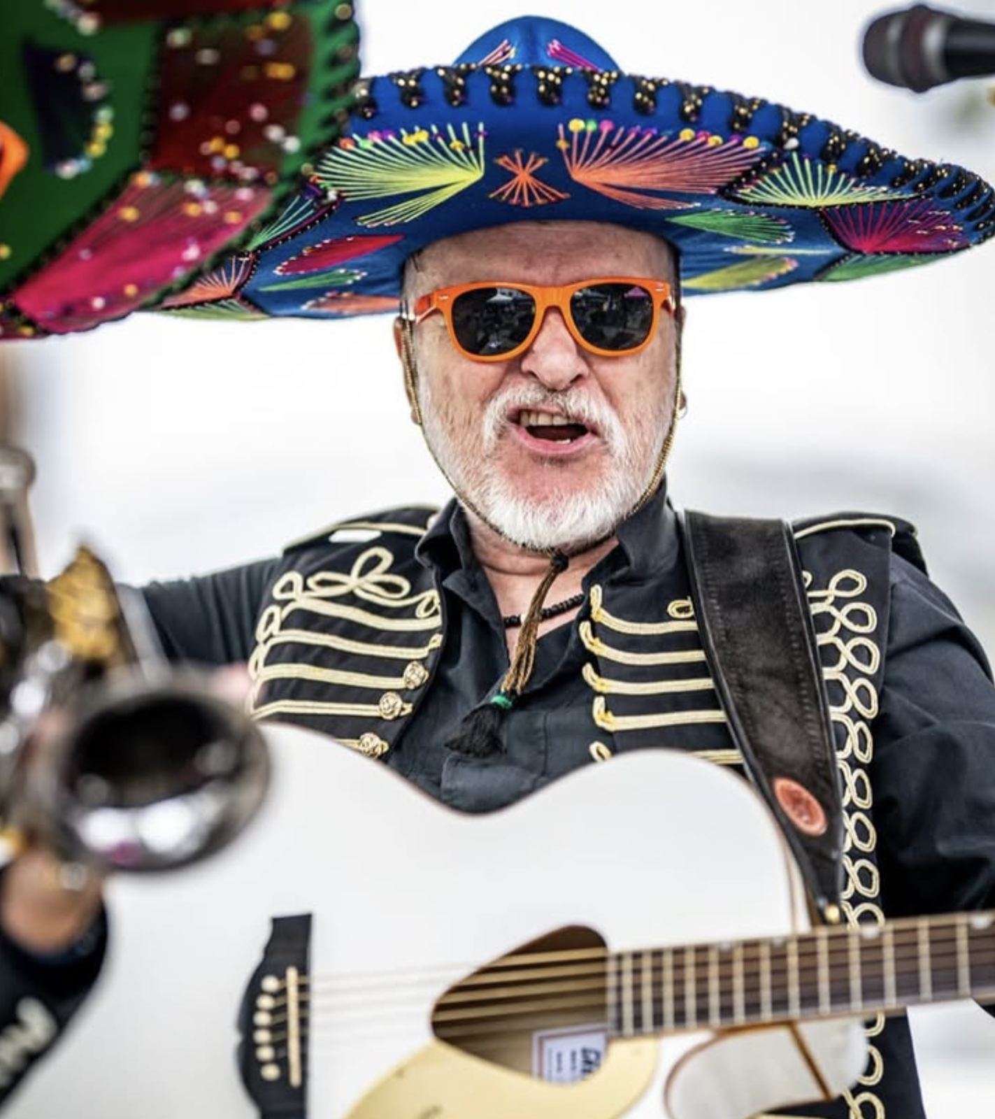 A singer in a sombrero and orange sunglasses playing guitar