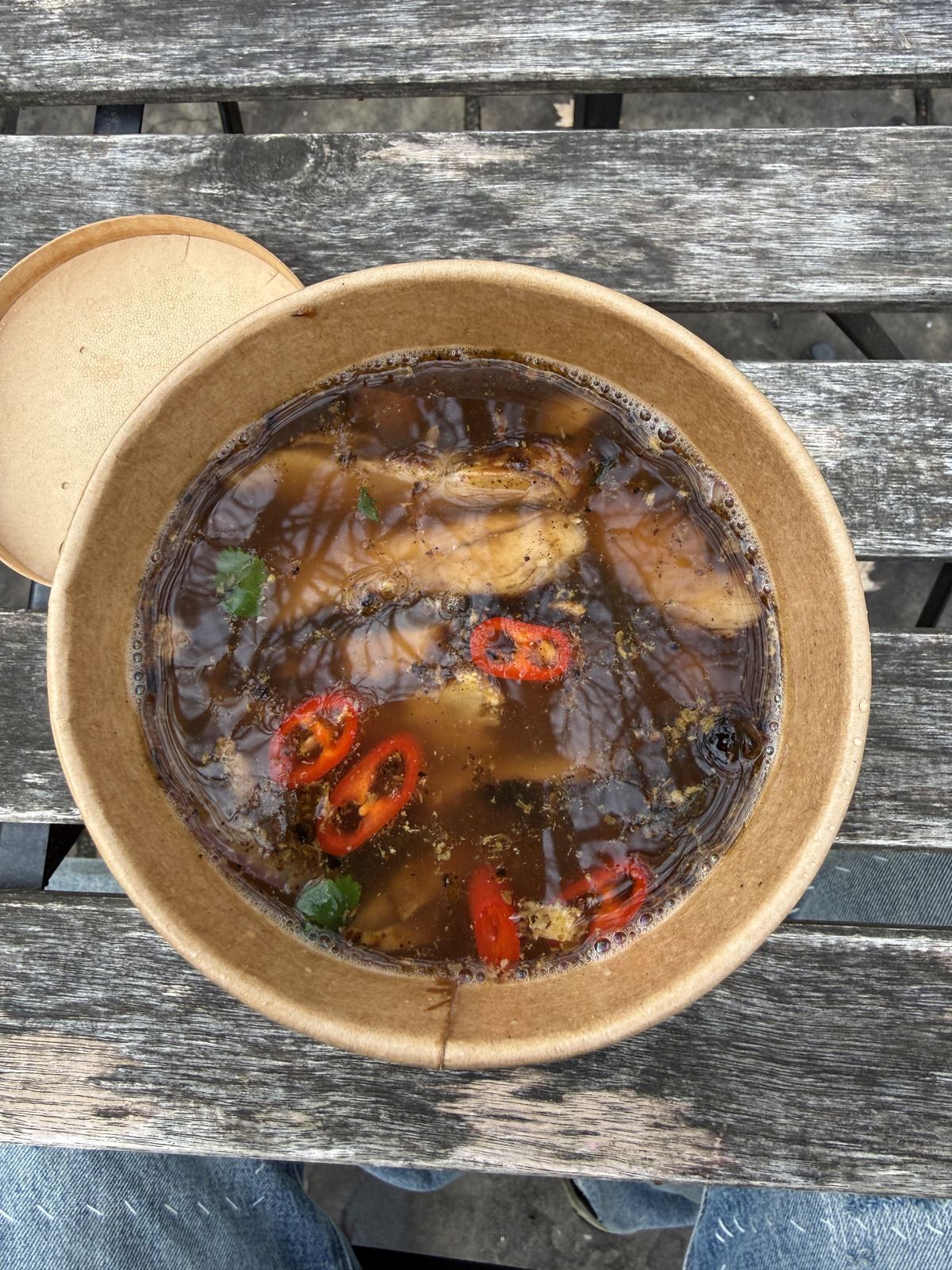 A bowl of chilli-topped soup on a wooden table